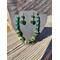 Jewelry set in the sun. This photo captures the vibrant emerald beads and shiny gold components in the sun.
